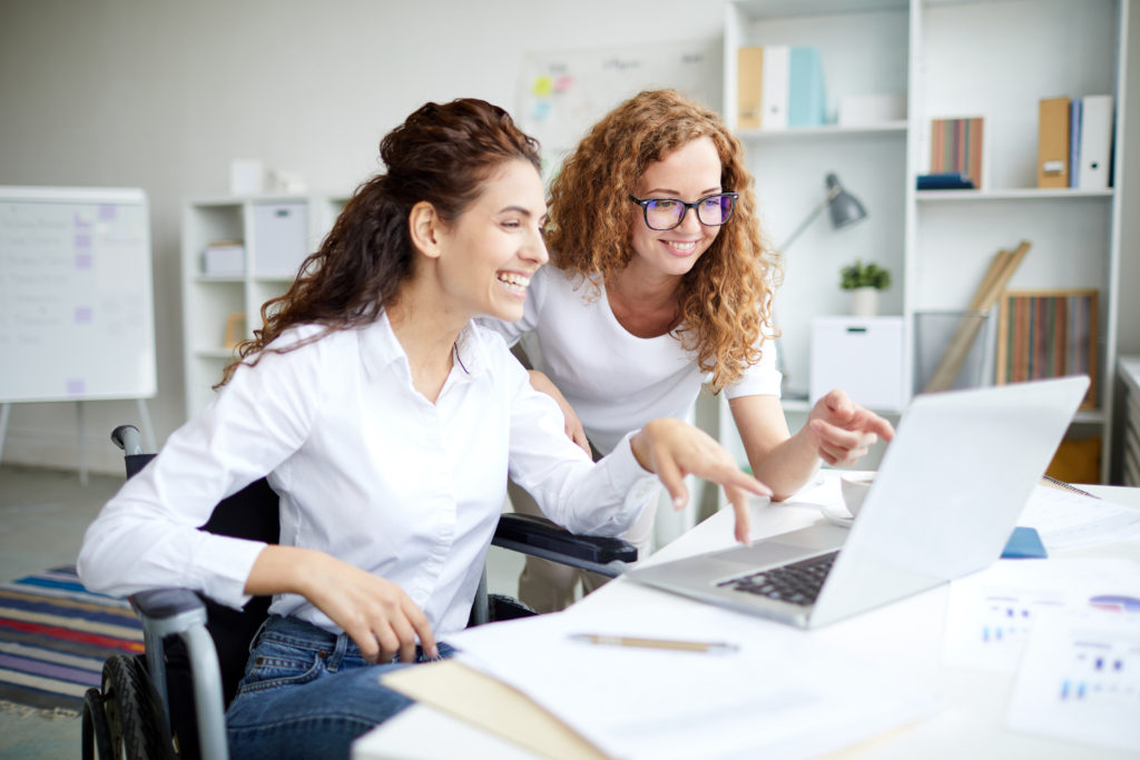 tow females looking at a computer and smiling